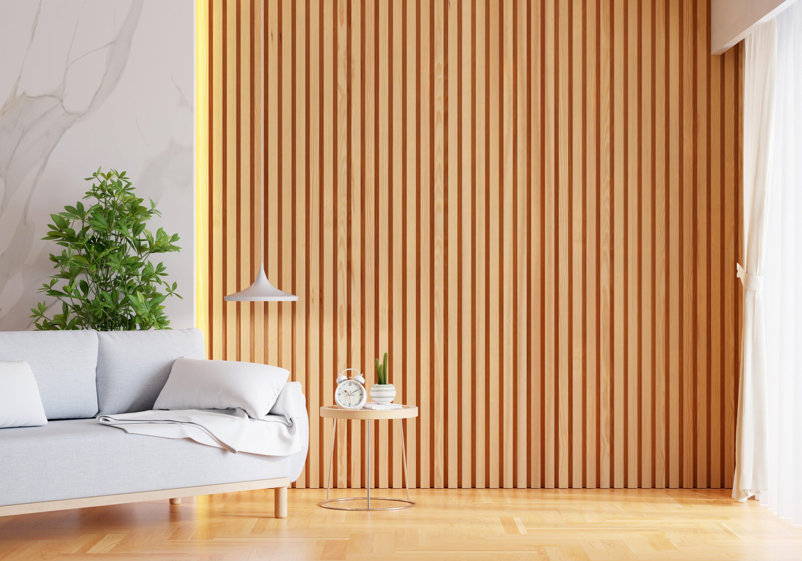 Bright living room with a light wooden slat wall, gray sofa, indoor plant, round side table, and sheer white curtains.