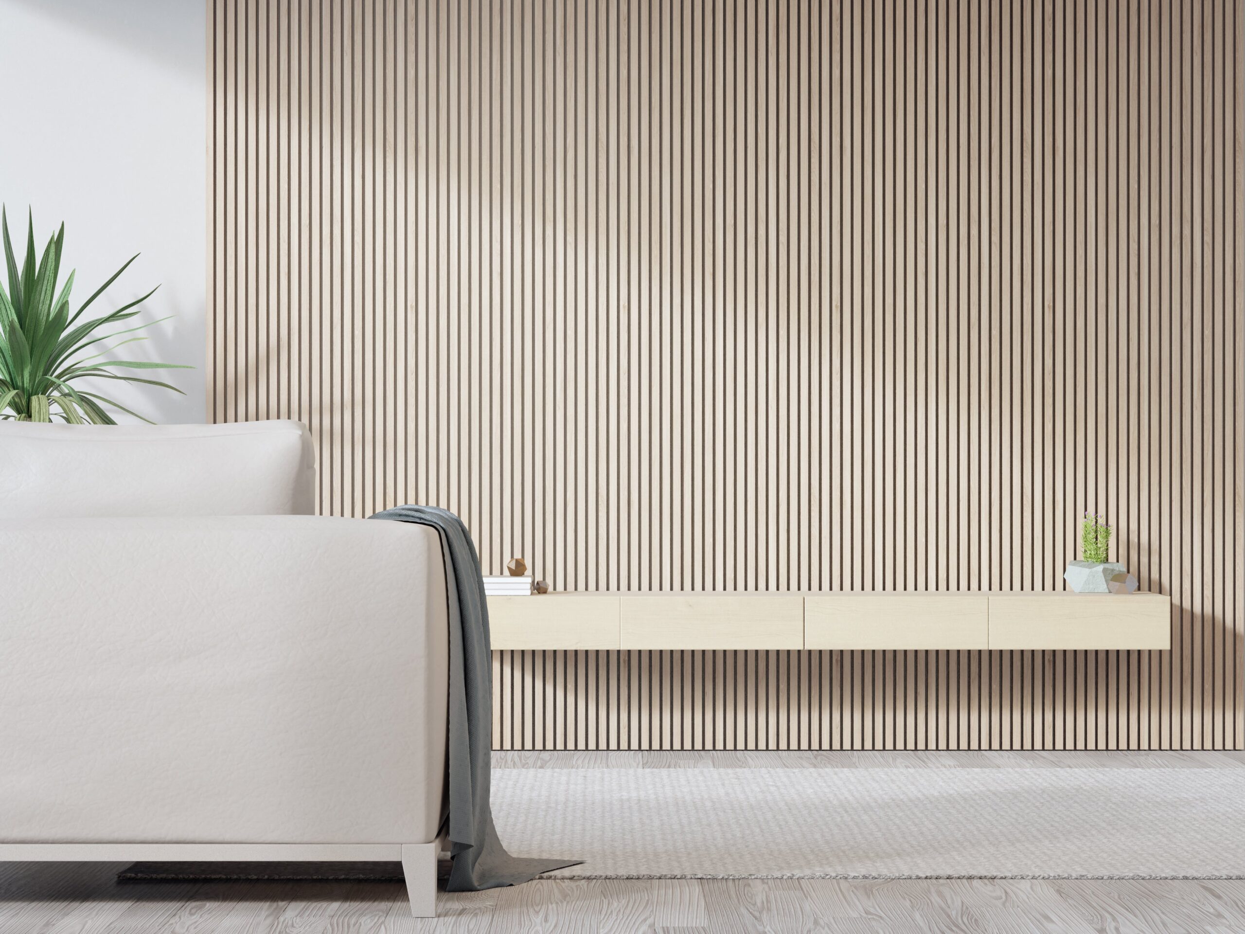 Minimalist living room with light beige wooden slat wall, white sofa, floating cabinet, and indoor plant in soft natural lighting.